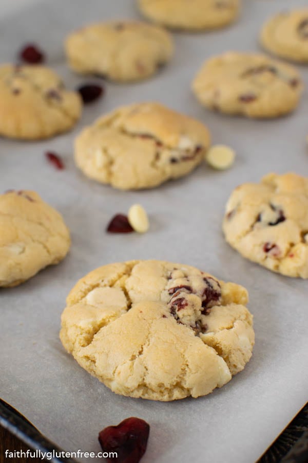 A baking tray with white chocolate cranberry cookies on it
