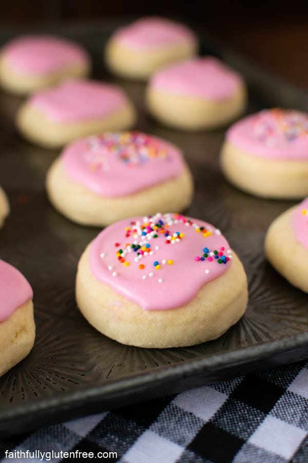 a cookie sheet with cookies topped with pink icing and sprinkles