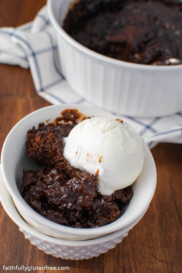 A bowl of chocolate pudding cake topped with vanilla ice cream
