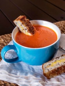 A bowl full of gluten free and dairy free tomato soup served with grilled cheese.