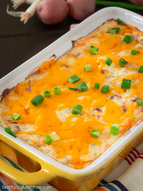 A potato dip topped with melted cheddar cheese and onion greens