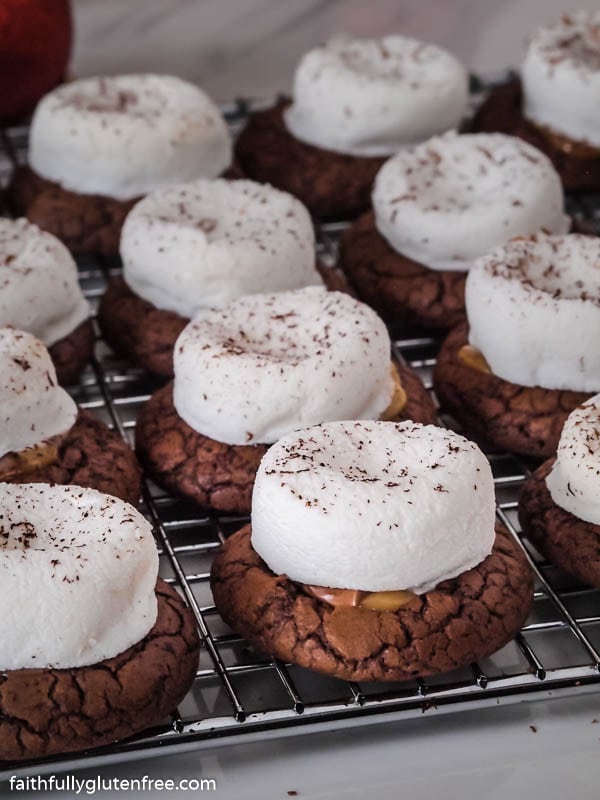 A cooling rack with chocolate cookies topped with marshmallows