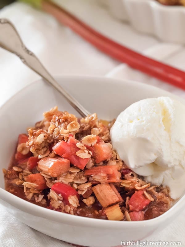 A bowl full of gluten free rhubarb crisp with a scoop of vanilla ice cream