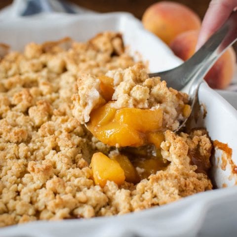 Peach Cobbler being spooned from a baking pan