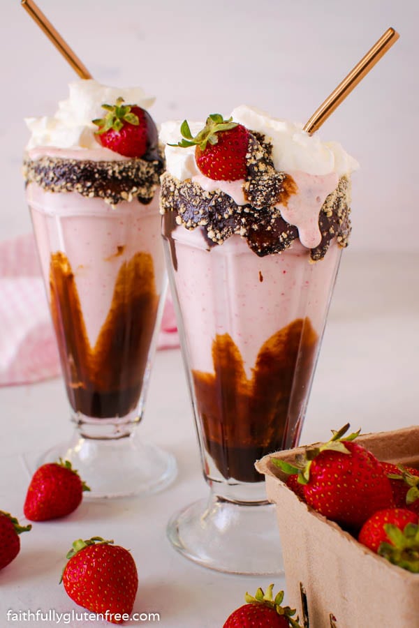 Two strawberry milkshakes with chocolate sauce in the glasses