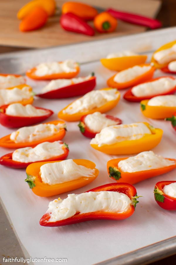 Mini sweet peppers stuffed with cheese on a baking sheet