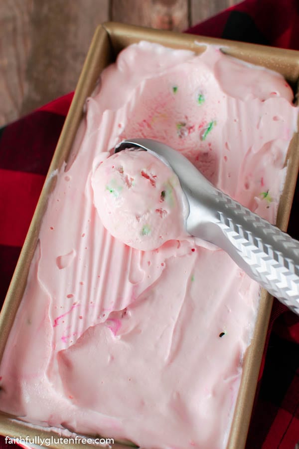 Loaf pan with pink candy cane ice cream and an ice cream scoop